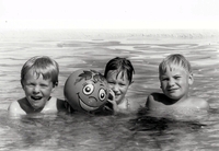 Three boys in the water with ball.