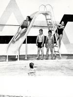 Swimmers on slide in pool.