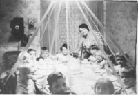"Birthday party for Arlie (Welsh) Freer at the home of Archie and Eliina Welsh on 1st Ave. in 1937. Doug Evans in the bottom "